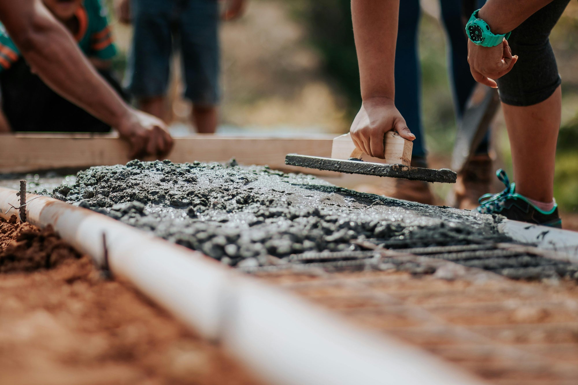 Close-up of people leveling wet concrete — representing Money-Lead’s foundation-building approach to financial strategy, structure, and creating long-term stability through solid groundwork.