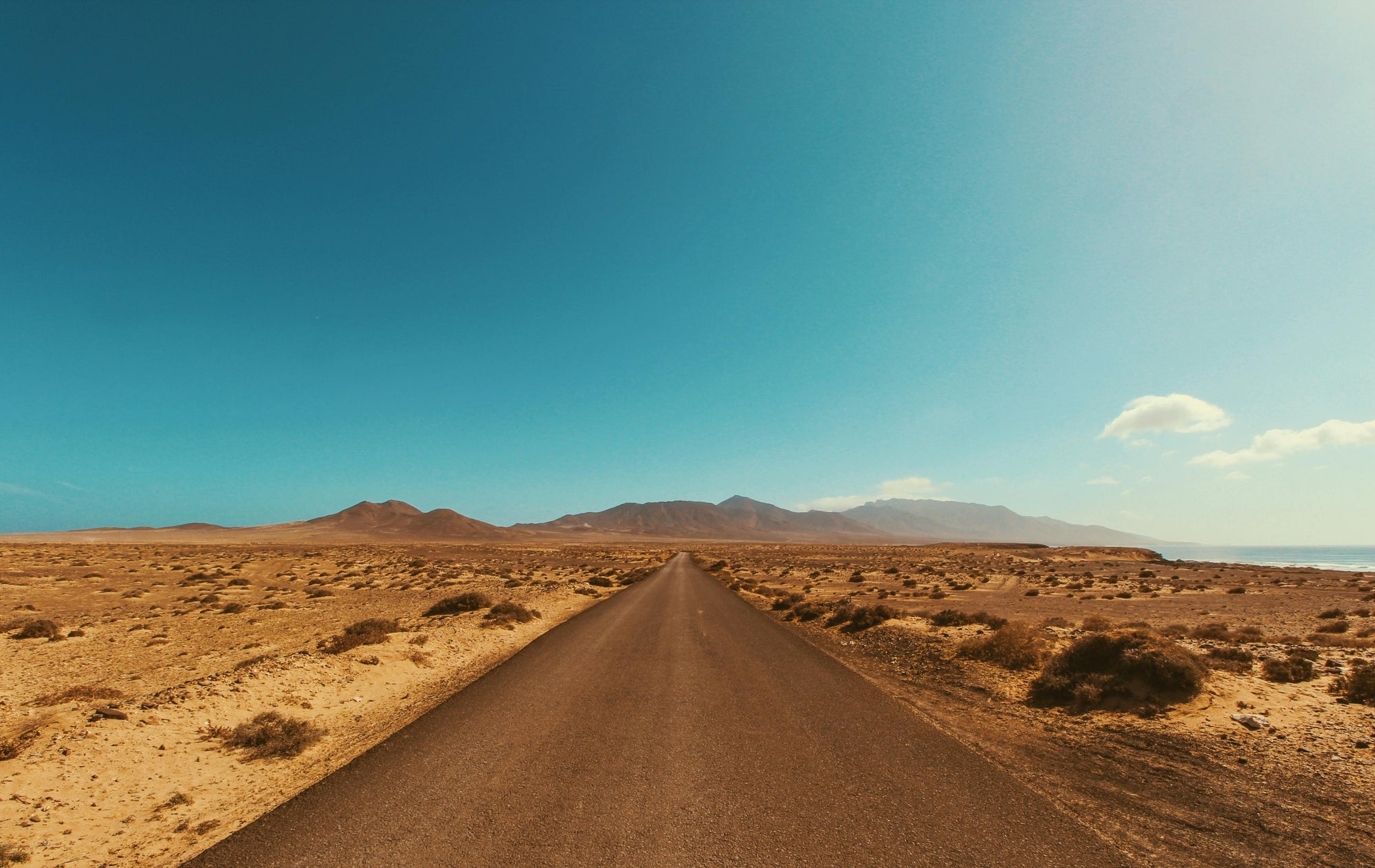 Empty winding road through a desert landscape under a clear blue sky during daytime — symbolizing Brainchild’s journey toward clarity, direction, and purposeful leadership.
