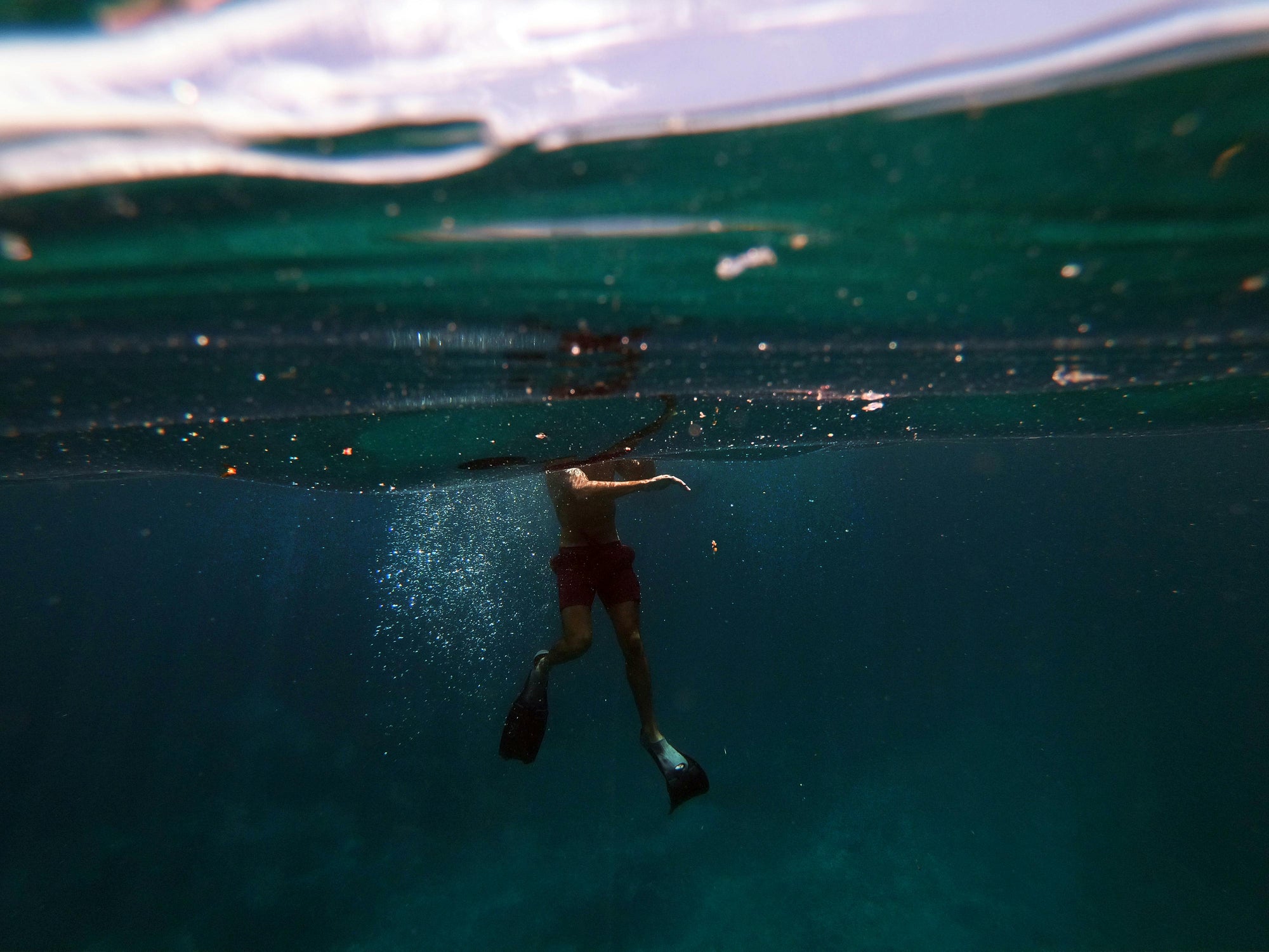 Underwater view of a person swimming with fins near the surface — symbolizing Brainchild’s depth of thought, exploration beneath the surface, and balance between clarity and creativity.